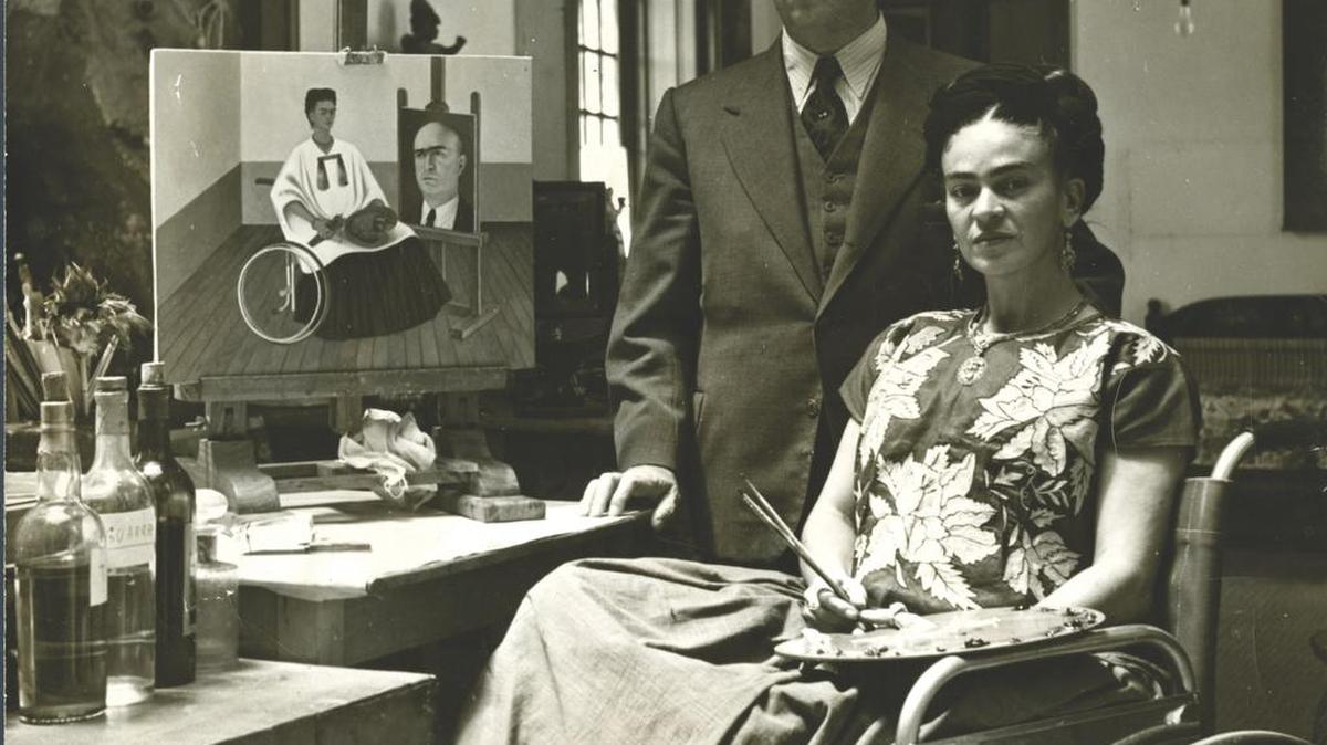 Frida and doctor Juan Farill in her studio in 1951, in front of her “Portrait of Doctor Farill,” a self portrait. From the Wolf Photography Collection