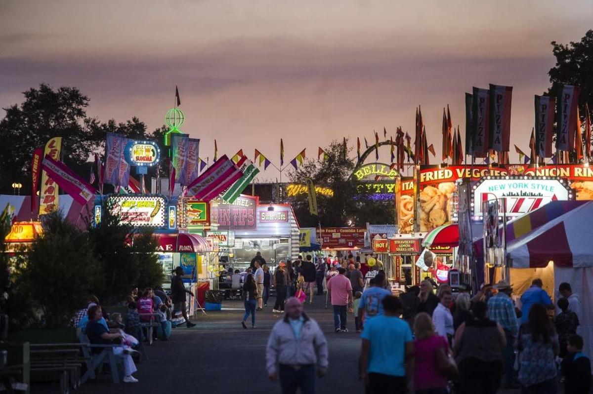 The sun sets over the bright lights of food stands at opening night of the Manatee County Fair in Palmetto. The fair continues through Sunday.