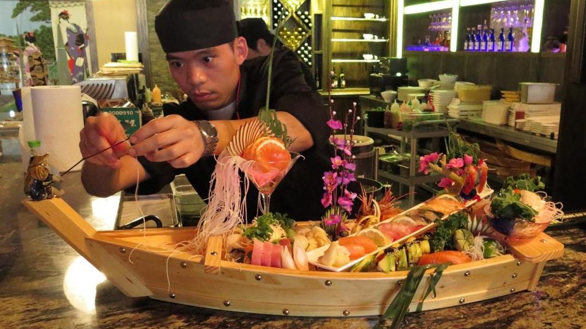 A sushi chef at Japanese restaurant Yuniku, threads a line through a fishing pole on a sushi and sashimi boat prepared for a customer. The restaurant is at 8341 Lockwood Ridge Road.
