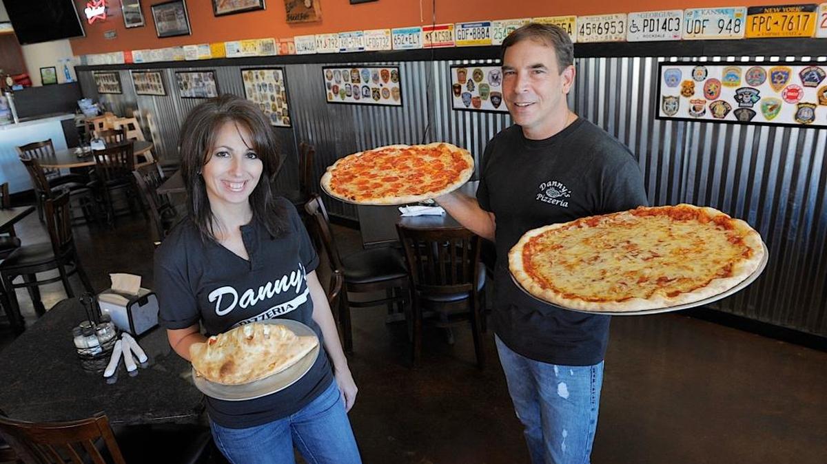 Danny’s Pizzeria owners Danny and Joan Fernandez hold a calzone, one of their most popular entrees, and a pair of hot New York style pizzas fresh from the oven in their expanded dining area. The restaurant is at 7220 Manatee Ave. W., Bradenton.