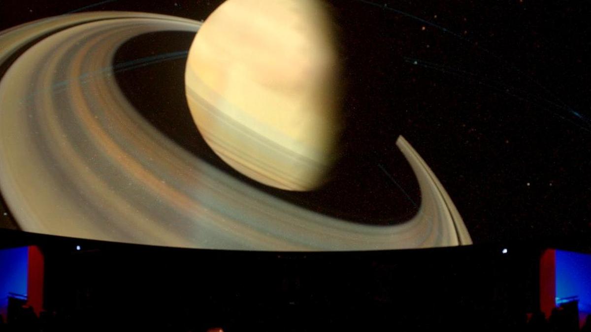 A spotlight illuminates reclining seats at bottom as the planet Saturn comes into view on the full-dome at the new Bishop Planetarium during a trial-run of the sophisticated digital projection equipment that powers its displays of the heavens.