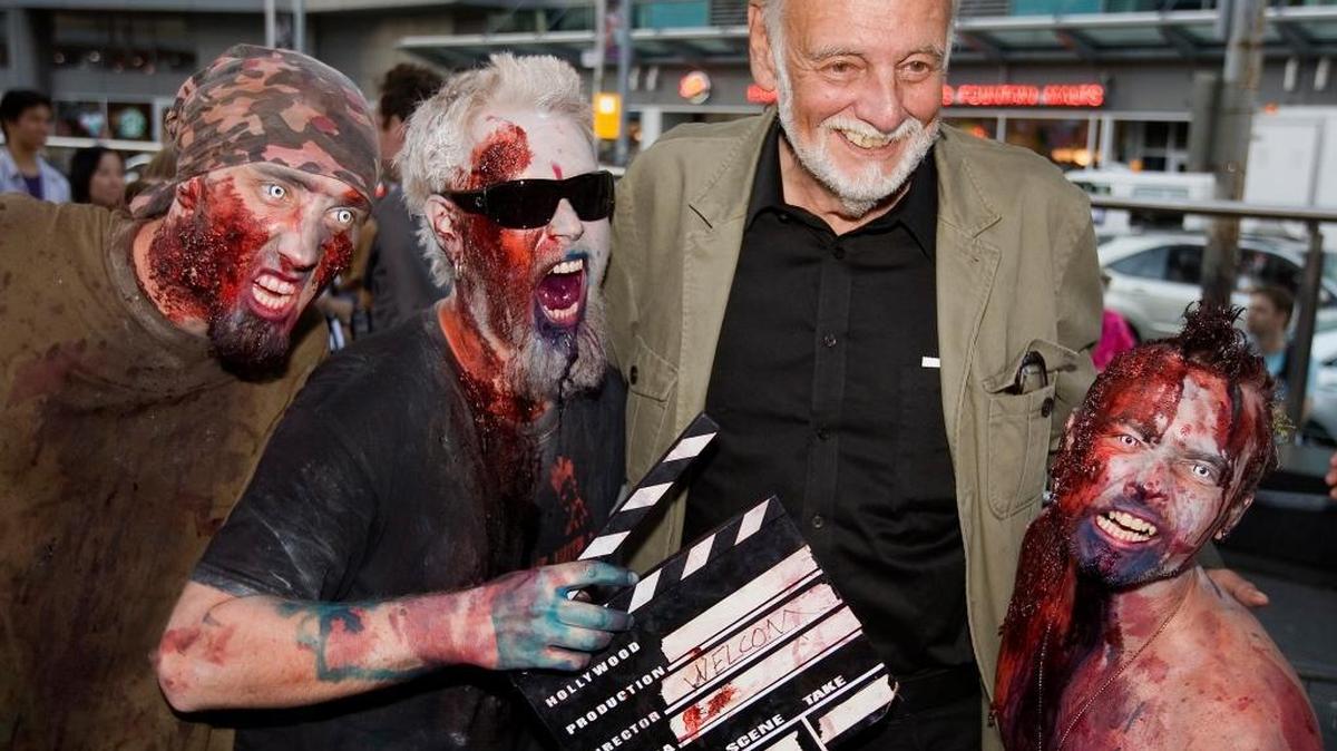 FILE - In this Sept. 12, 2009, file photo, director George Romero poses with some fans dressed as zombies after accepting a special award during the Toronto International Film Festival in Toronto. Romero, whose classic "Night of the Living Dead" and other horror films turned zombie movies into social commentaries and who saw his flesh-devouring undead spawn countless imitators, remakes and homages, has died. He was 77. Romero died Sunday, July 16, 2017, following a battle with lung cancer, said his family in a statement provided by his manager Chris Roe.