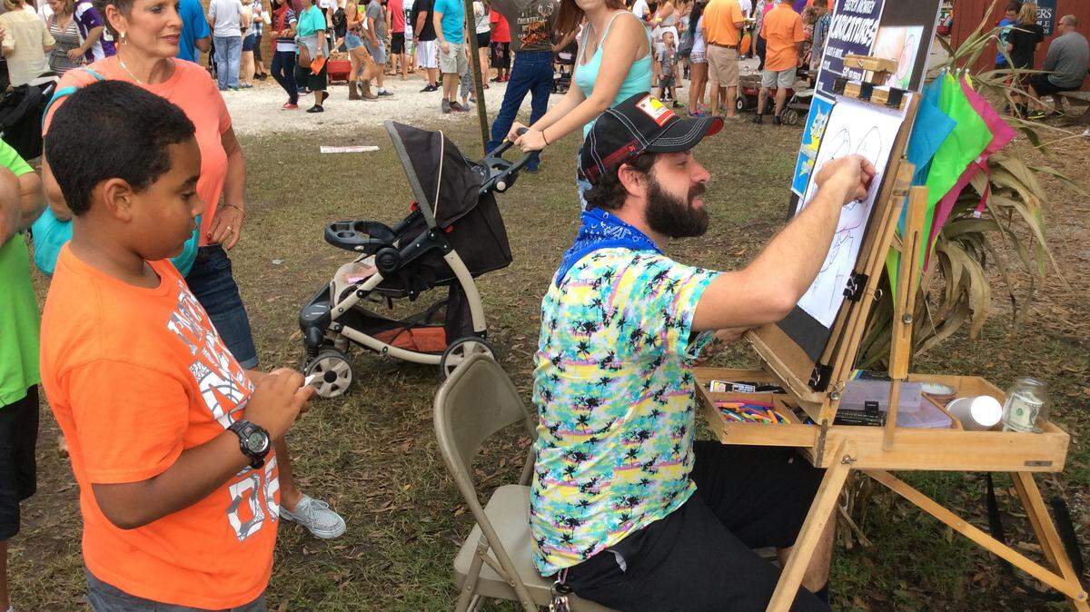 As interested people look on, caricaturist Justin Dick from Clearwater makes a portrait during Sunday's Hunsader Farms Pumpkin Festival. 
 RICHARD DYMOND/Bradenton Herald
