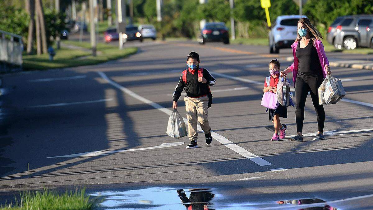 08/09/21—A family crosses the road on the way to Sea Breeze Elementary School on the first day of classes in Manatee County.