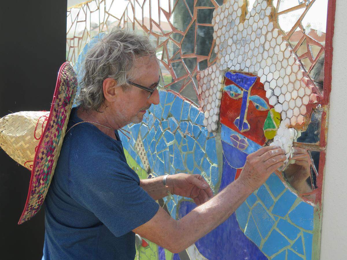 James Simon, 64, adds hair to a musician depicted in a mosaic tile mural he created that is being installed on the north side of the City Centre parking garage.