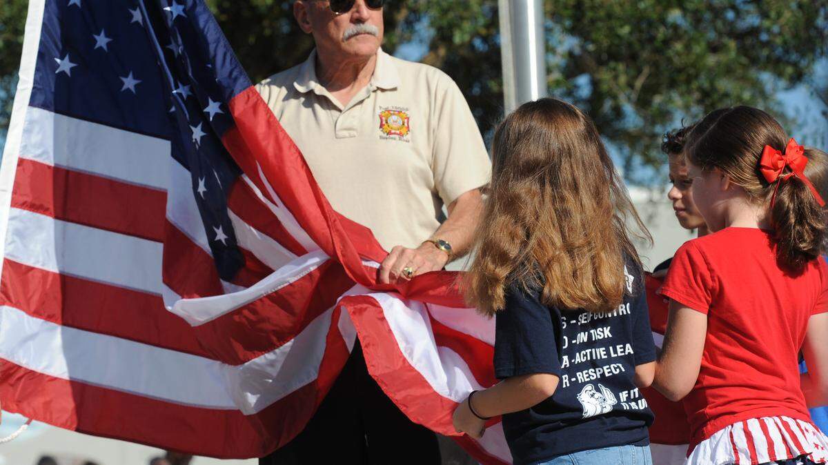 Members of the Braden River VFW Post 12055 assist students as they prepare to the raise the flag during the school's Veterans Day celebration in November 2015. 
 File Photo/Bradenton Herald