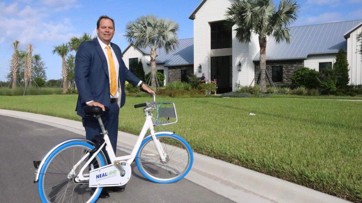 John Neal, president of Neal Land & Neighborhood, is shown with one of the bicycles that residents of North River Ranch in Parrish can use to get around their community, which is being designed to have about 24 miles of trails and paths.