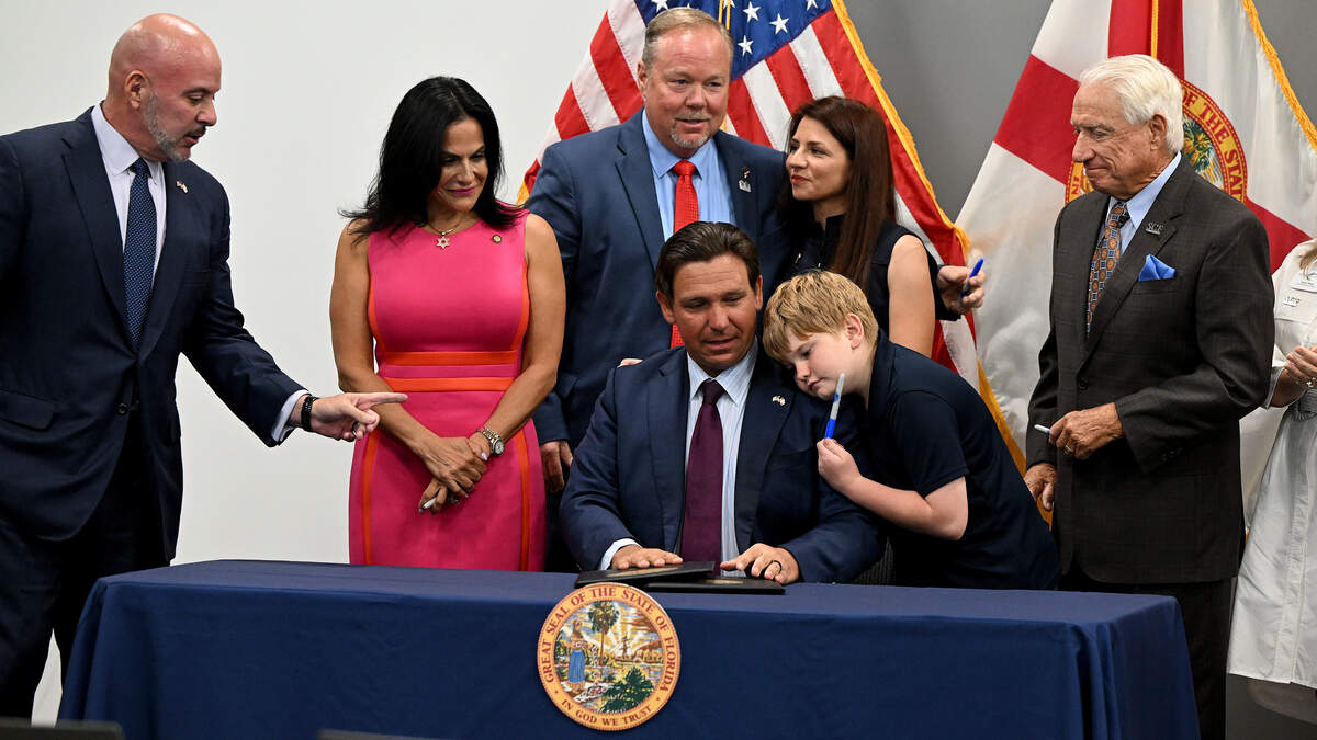 Florida Gov. Ron DeSantis signed two bills enacting stricter regulations on local governments’ ability to raise taxes and creating more transparency at State College of Florida on June 24, 2026. Charlie Smith, 12, hugs the governor after receiving a pen from the governor.