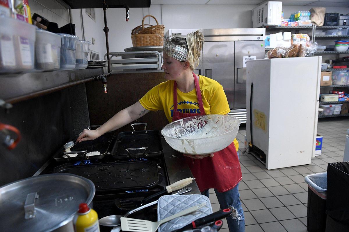 Courtney Cummings prepares food as Bayshore High football players load up their plates with pancakes, bacon, fruit and vegetables at Church of the Cross, which prepares a pregame meal for them.