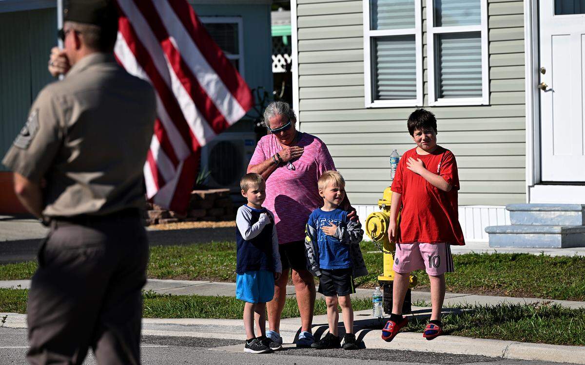 A family puts their hands on their hearts as the flag carried by Army First Sgt. Brian Webb leads the parade.