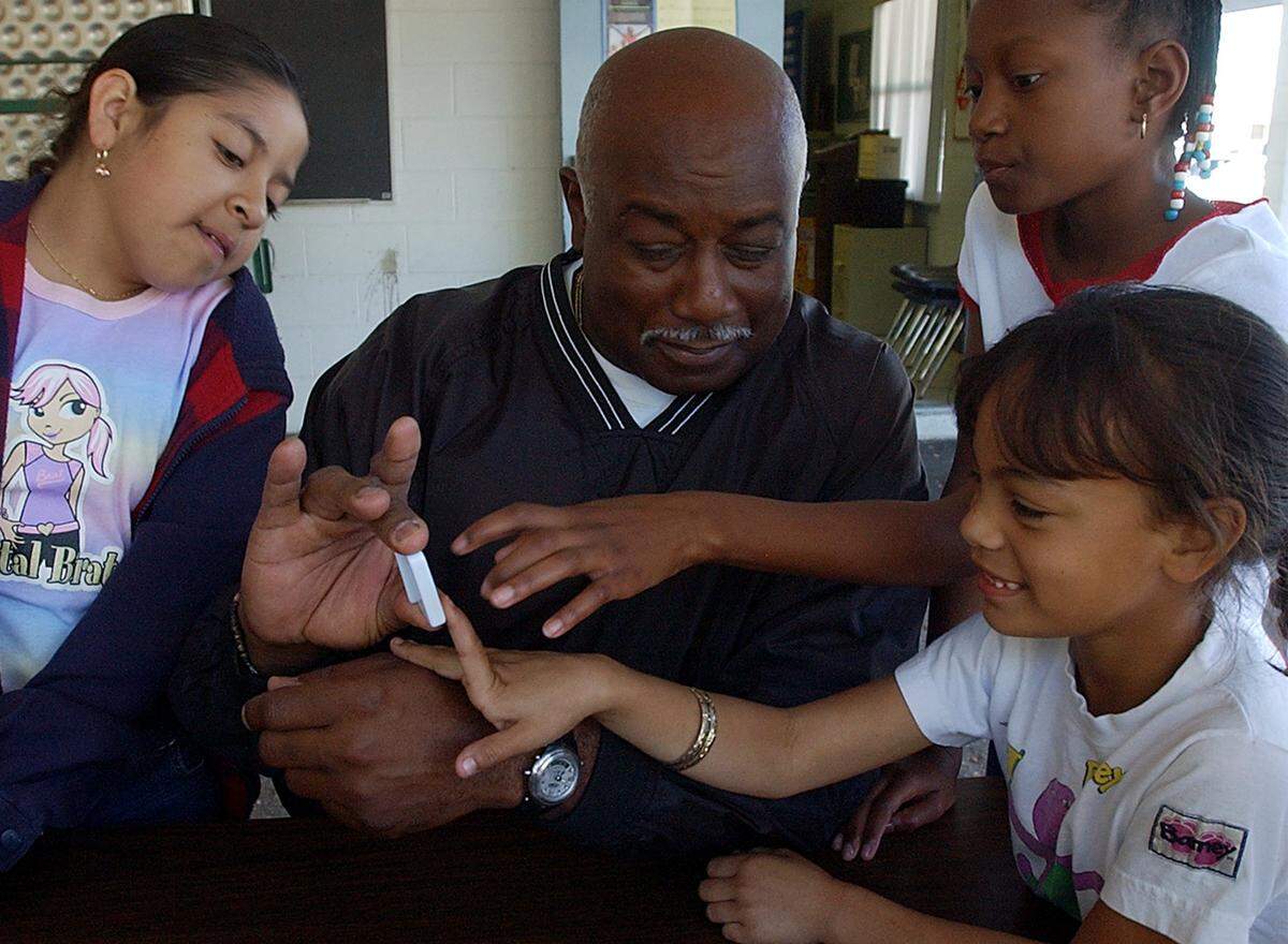 Iztel Palacios, 10, Kwanna Ferguson, 10, and Yesenia Marrero, 7, help their Director, Willie Cooper, while playing dominoes at the East Bradenton Boys and Girls Club in 2004.