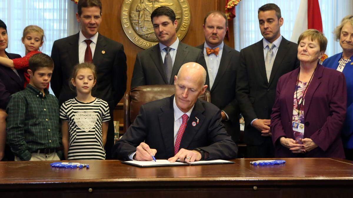 Floirda Gov. Rick Scott, center, signs the children with special abilities bills in his office at the state Capitol as legislators with their families look on, Thursday, Jan. 21, 2016, in Tallahassee, Fla. (AP Photo/Steve Cannon)