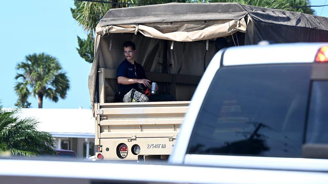 A man with a medic badge rides in the back of a truck as heavy equipment crosses the Cortez Bridge to Anna Maria Island in the aftermath of Hurricane Helene in Manatee County on Friday, Sept. 27, 2024.