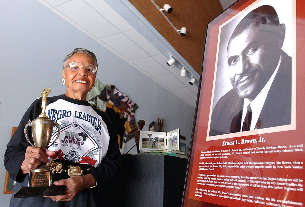 5/9/2002--Fredi Brown holds one of her late husband’s, Ernest Brown, Jr., golf trophies that is on display next to his portrait that welcomes visitors to the Family Heritage House Museum at Manatee Community College. The display is part of the “From Obscurity To Excellence” an exhibit celebrating black achievement in sports.