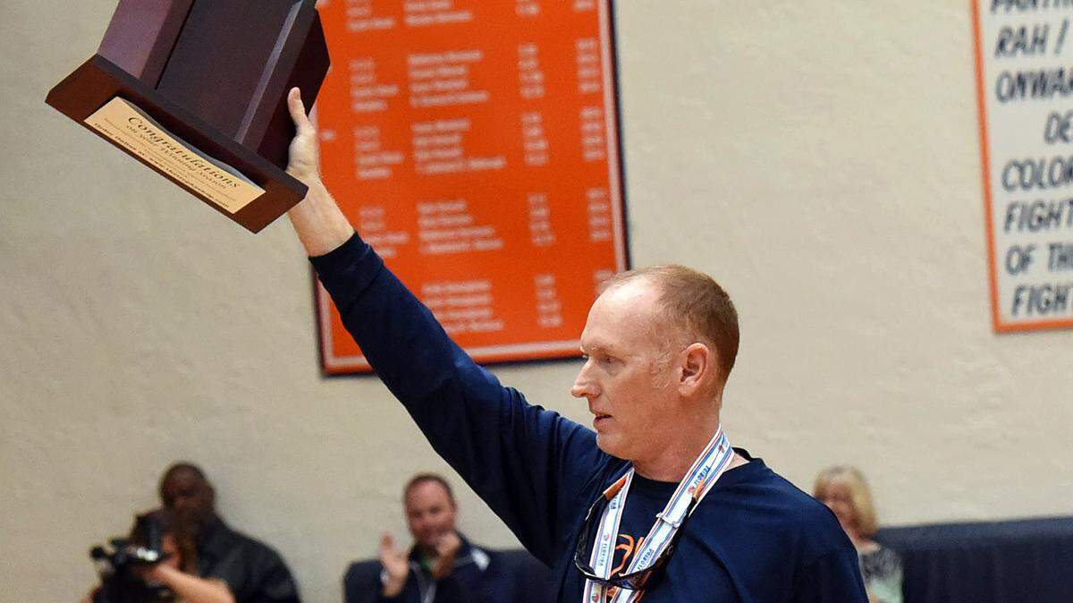 Bradenton Christian’s basketball coach Scott Townsend holds up their trophy during a welcome back pep rally for the basketball team after bringing home the runner-up title to the state championships in 2016.