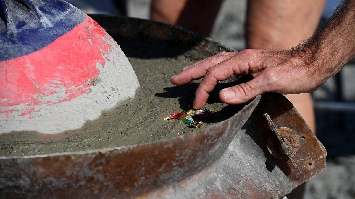 Tom Ries adds a colorful piece of his mother, Gisela’s, costume jewelry to an eternal reef with her cremated remains incorporated into the structure. “This will attract a lot of fish,” said Ries, who said his mother loved fishing.