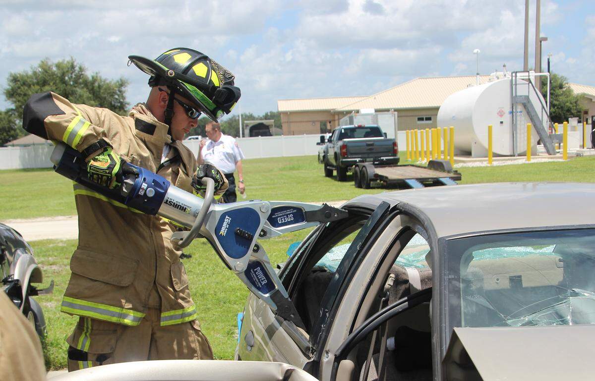 A Parrish firefighter takes apart a door on an old Chevrolet with new life-saving equipment the department received this week from Firehouse Subs Public Safety Foundation.