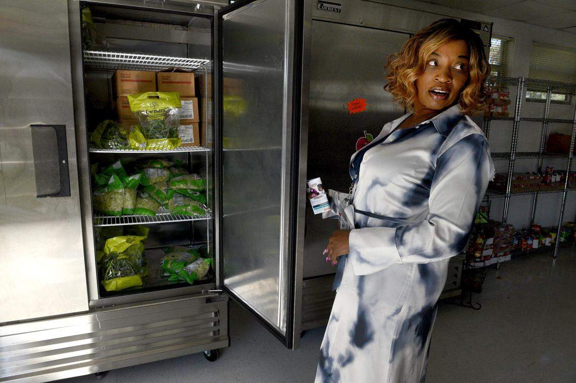 Vanessa Goldsmith holds open a refrigerator door in the school food pantry to show the fresh vegetables available. The school is a Community school, with a medical center, food pantry, and other supportive services for the students and their families.