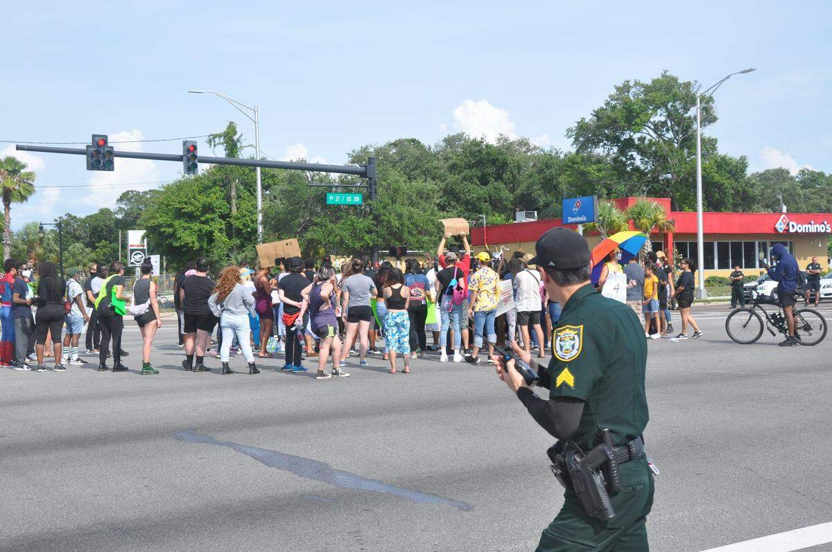 A Manatee County Sheriff’s Office deputy watches as protesters on Saturday morning shut down the intersection of First Street and Martin Luther King Jr. Avenue in Bradenton. The demonstrators were protesting the death of George Floyd on May 25, after a now-former police officer pinned him down to the ground by placing his knee on Floyd’s neck.