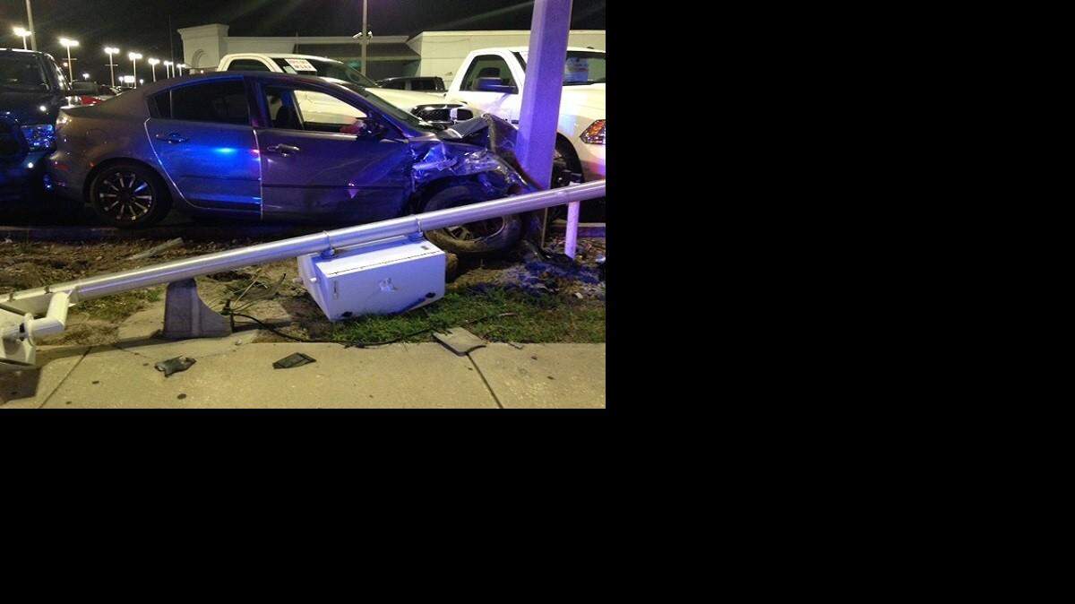 A vehicle that crashed into an auto dealership in Tampa comes to rest against a utility pole.