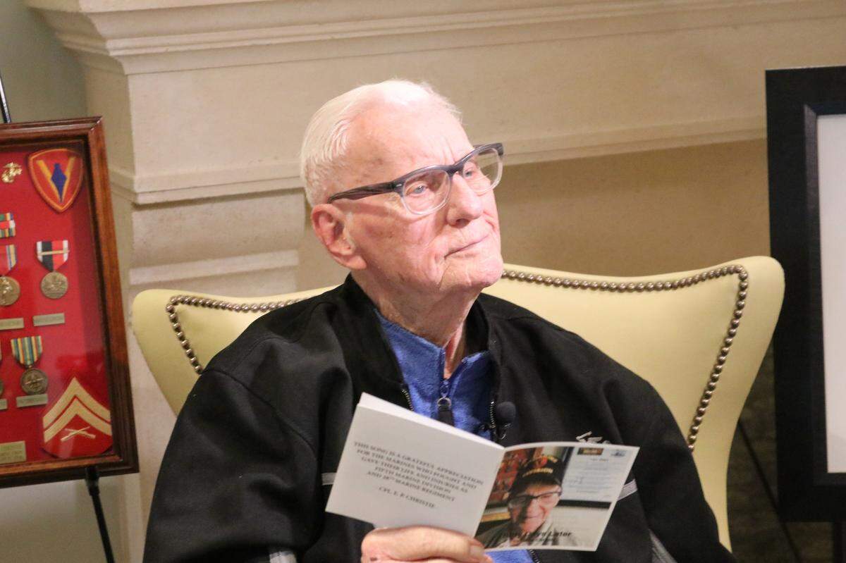 Gene Christie, 96, reads some of the lyrics for “Thirty Days Later,” a song written for fellow Marines who died on Iwo Jima during World War II.