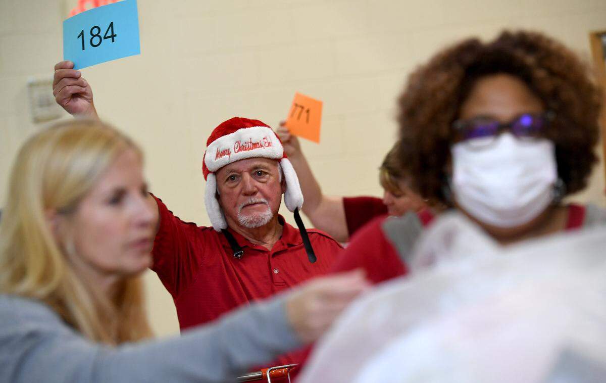 Leonardo Burman holds up a number to get toys for a family as dozens of volunteers gather toys that were collected for 786 families on the Salvation Army’s Angel Tree Distribution Day. Families registered in September to receive presents for their children along with a turkey or ham. The distribution was drive-through style, with volunteers working together to make the event run smoothly.