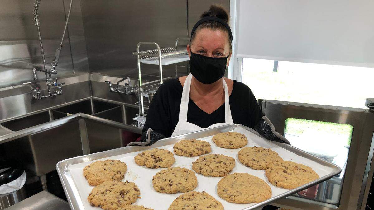 Cindy Unzicker, owner of Bite Me Cookies by Cindy, removes a tray of fresh-baked cookies from the oven. She delivers the cookies to a dozen Manatee County neighborhoods a month.