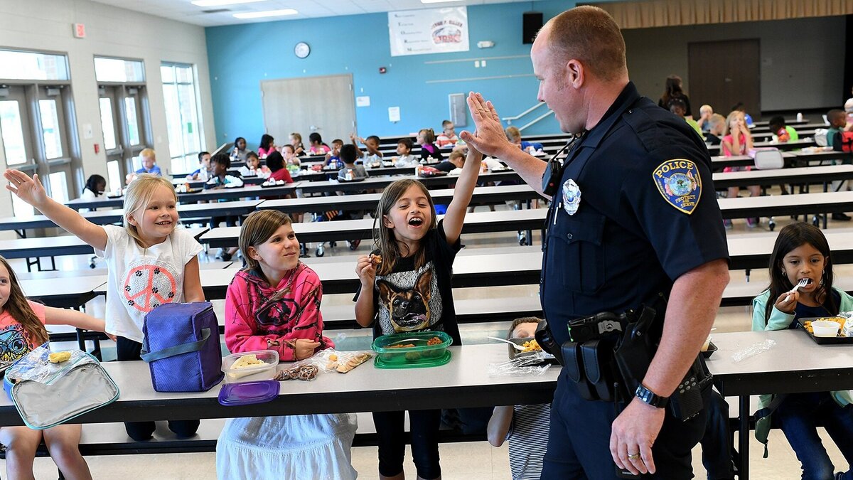 Bradenton Police officer Rusty Ackerman gives high fives to students at lunch as he fills in as a school resource officer at Miller Elementary School Wednesday. The Manatee County School Board and the Board of County Commissioners held a joint meeting on Wednesday to discuss school resource officers, emergency shelters and FEMA reimbursments.