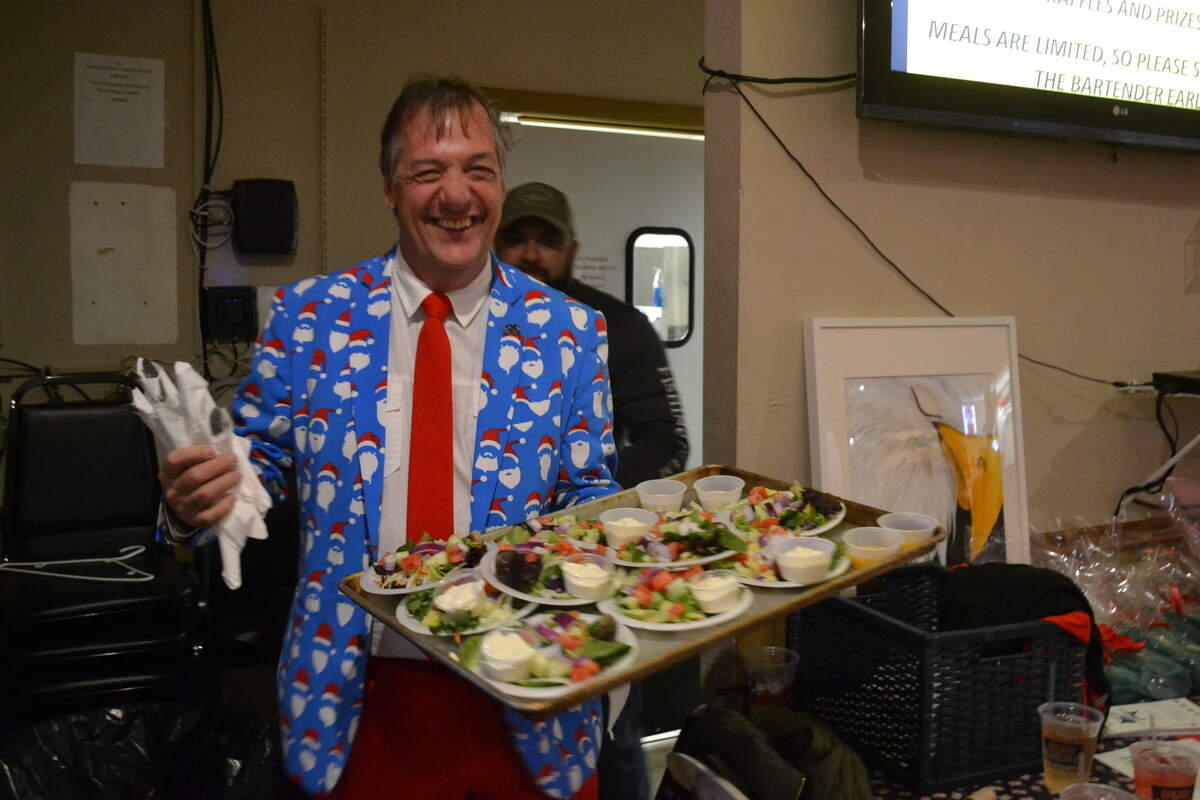 Bob Slicker, general manager of Swordfish Grill and Tiki Bar in Cortez, emerges from the kitchen of VFW Post 10141 with tray of salads to serve to veterans and their families who were attending a surprise holiday event.