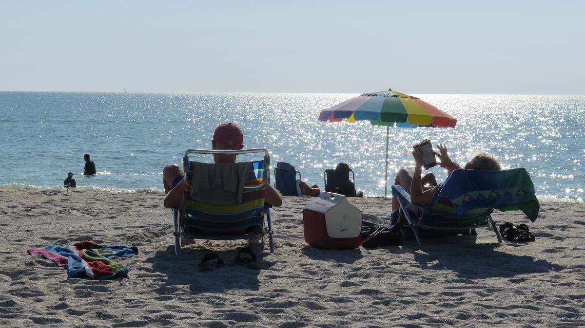 A couple lounges in the sun on Manatee Public Beach. For the past few weeks, red tide has cleared out of the area, according to officials, and businesses are making more money than before.