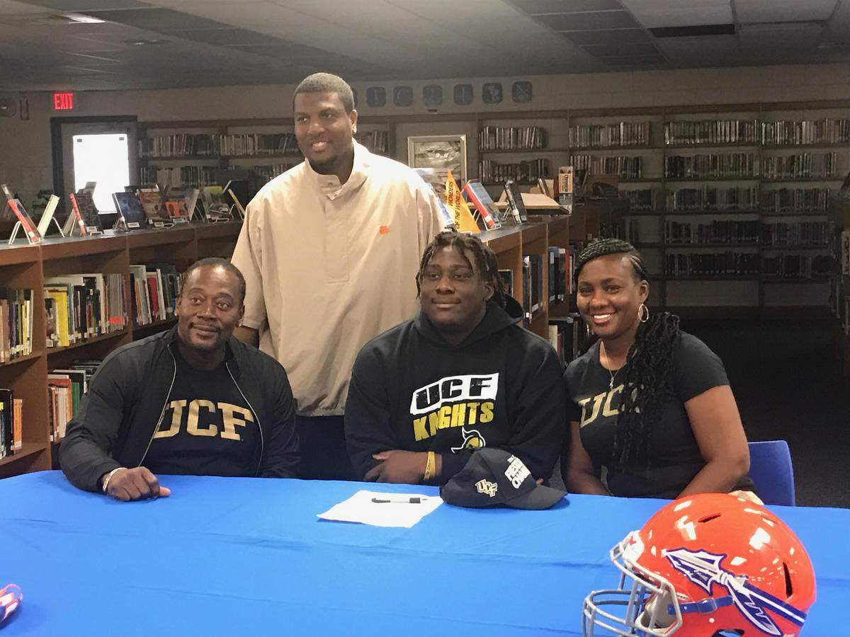 Southeast’s Kam’ron Green is flanked by his parents and Seminoles head coach Brett Timmons (standing) as he signs his letter-of-intent with UCF on Wednesday.