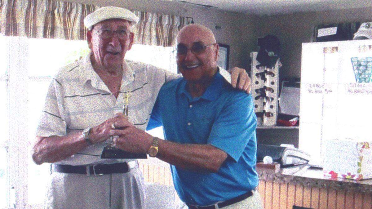 Warren Rossen, left, accepts a trophy from Joe Accetura in recognition of his winning the Greens of Manatee men's senior golf league in March. Rossen is 97 years old.