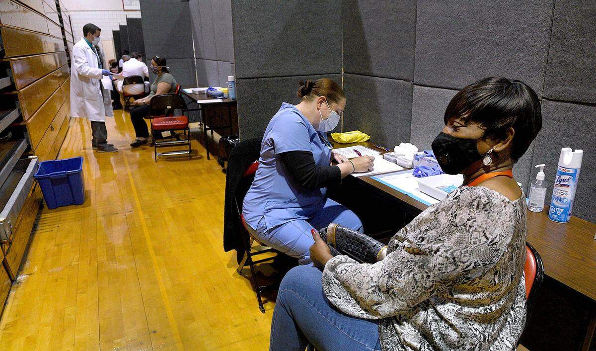 03/17/21--Vanessa Goldsmith, right, waits for her shot from Laura Browning this week. MCR Health vaccinated teachers and other employees of all ages with the Moderna vaccine at the Palmetto High School gymnasium.