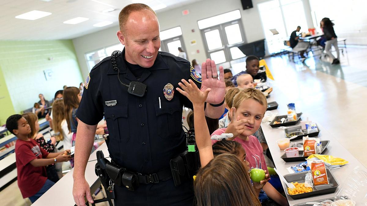 Bradenton Police officer Rusty Ackerman gives high fives to students at lunch as he fills in as a school resource officer at Miller Elementary School Wednesday. The Manatee County School Board and the Board of County Commissioners held a joint meeting on Wednesday to discuss school resource officers, emergency shelters and FEMA reimbursments.