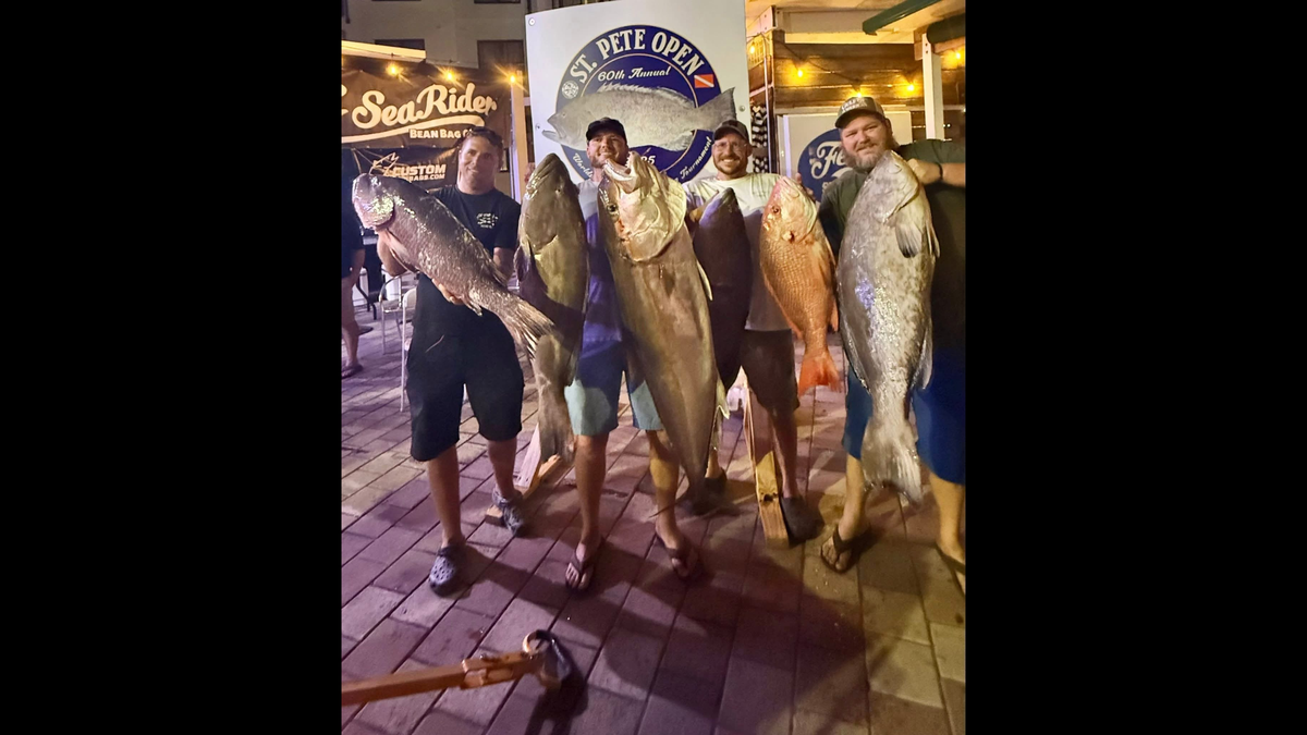 Chad Tripp (right) and his teammates pose with their fish during the St. Pete Open spearfishing competition.