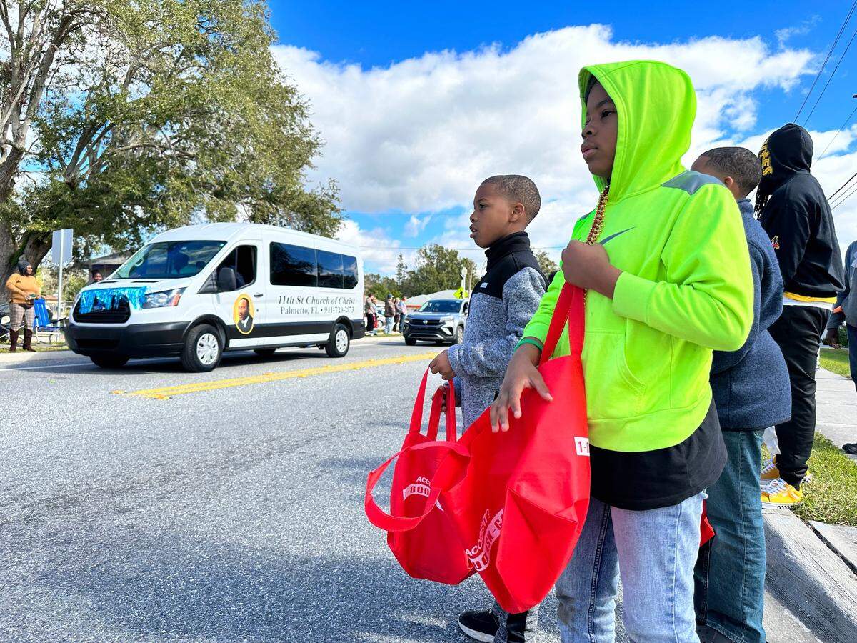 Dewight Crosby and Josiah McNeal of Palmetto stand along the parade route waiting on beads and candy to be thrown their way on Saturday, Jan. 14, 2023.