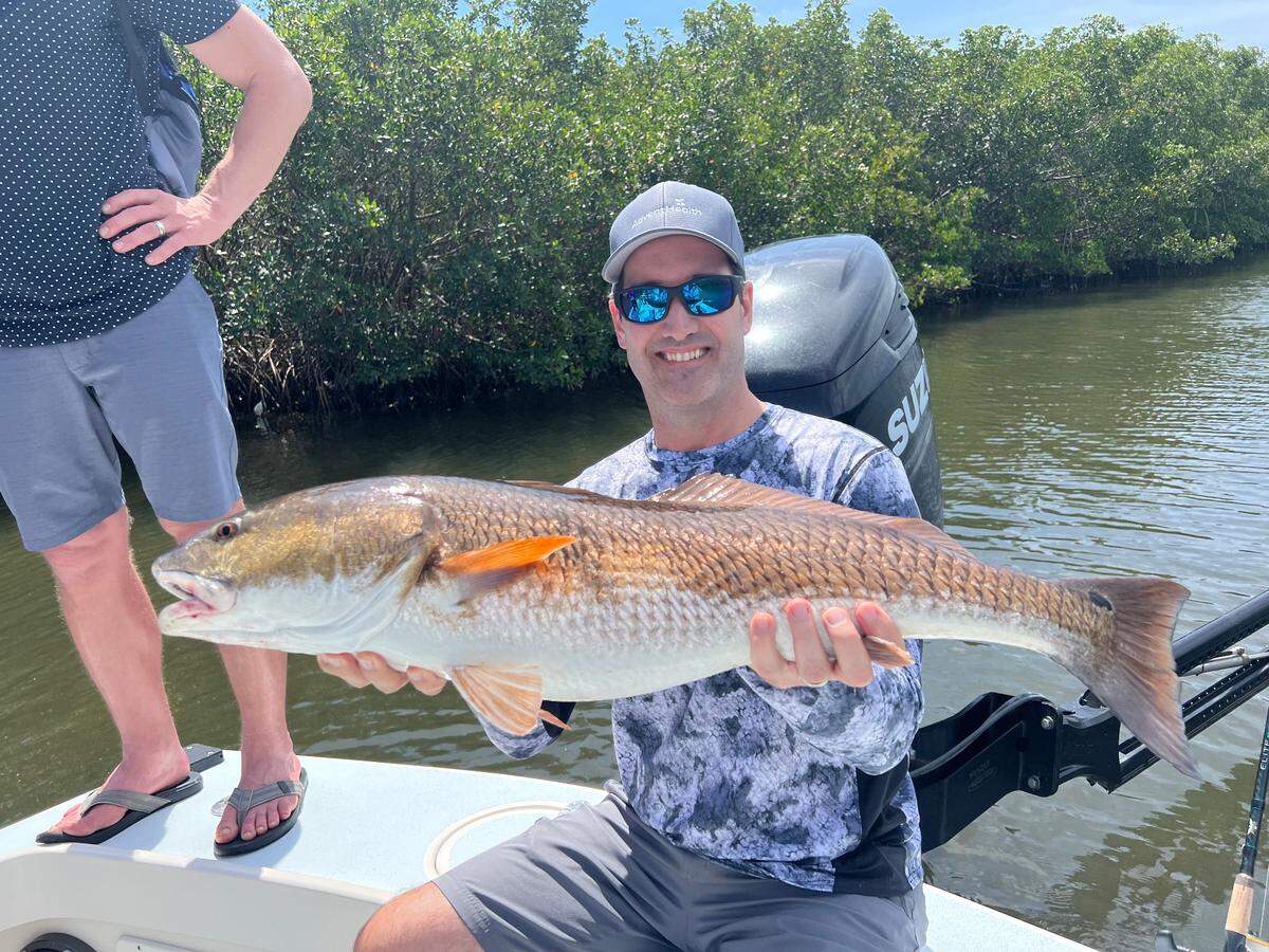 Jason Dunkel, president and CEO of AdventHealth in the Heartland Region of the West Florida Divison, poses with a 35-inch redfish caught with Capt. James Beers in a Tampa Bay creek during the AdventHealth Foundation’s West Florida Fishing Tournament.