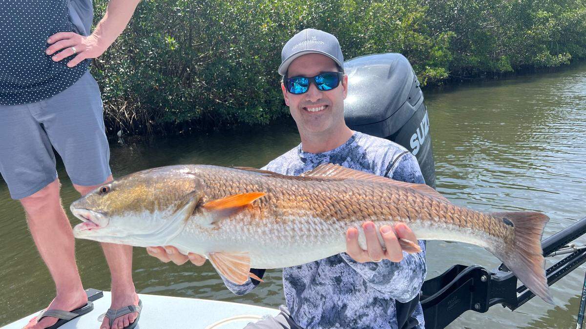 Jason Dunkel, president and CEO of AdventHealth in the Heartland Region of the West Florida Divison, poses with a 35-inch redfish caught with Capt. James Beers in a Tampa Bay creek during the AdventHealth Foundation’s West Florida Fishing Tournament.