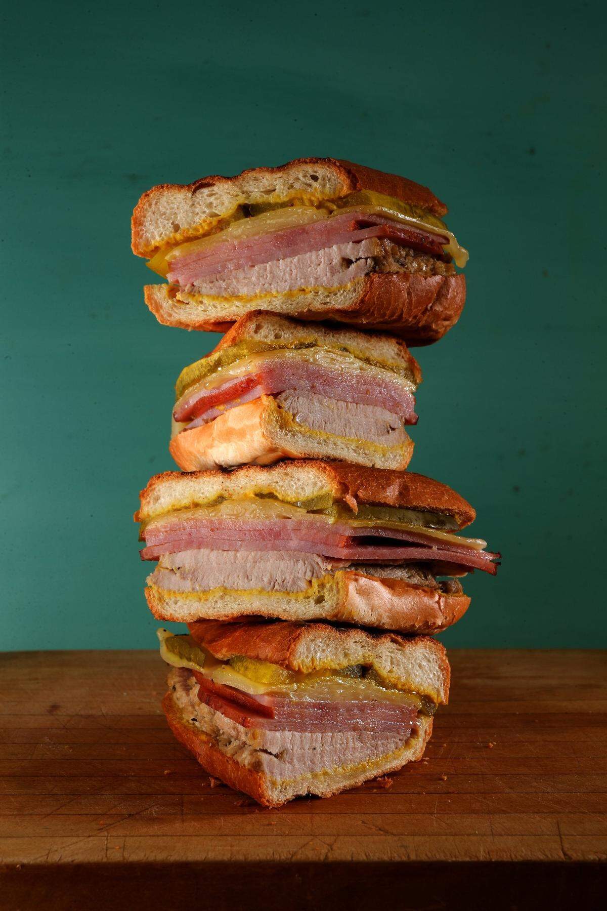 A traditional Cuban sandwich recipe calls for sliced ham, roast pork with a citrusy marinade (called mojo) and Swiss cheese layered in a loaf of Cuban bread. The sandwich is then garnished with pickles and mustard.