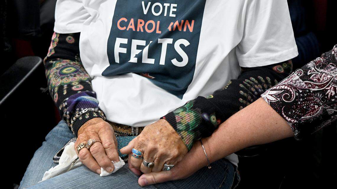 Friends hold hands at a meeting of the Manatee County Commission during a tribute to Carol Ann Felts on March 3, 2026.