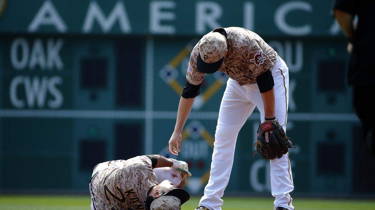 Pittsburgh Pirates shortstop Jung Ho Kang, left, is helped by teammate Neil Walker after injuring his left leg turning a double play Sept. 17 against the Chicago Cubs in Pittsburgh.ASSOCIATED PRESS