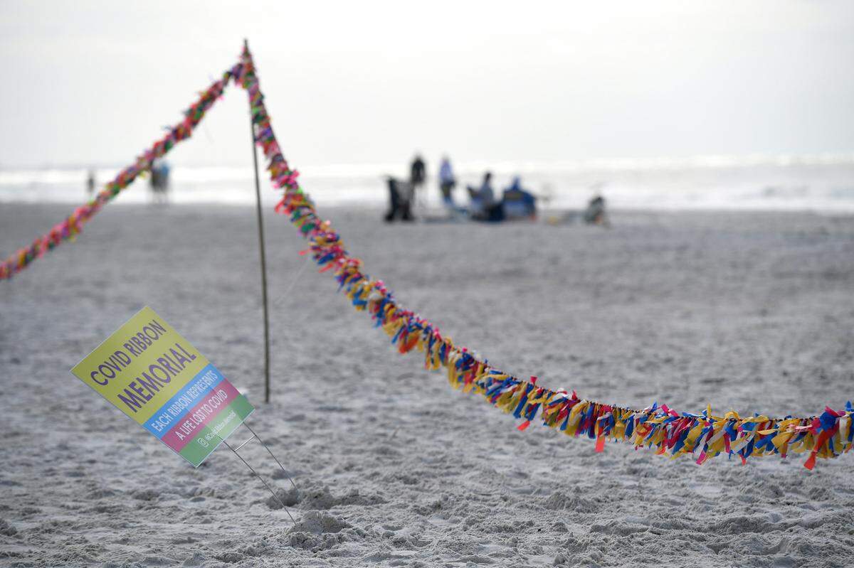 02/16/21--A group of people led by Cathy Tobias hold a memorial created from ribbons and stretching 250 yards to remember the almost 27,000 people lost to COVID-19 in Florida.