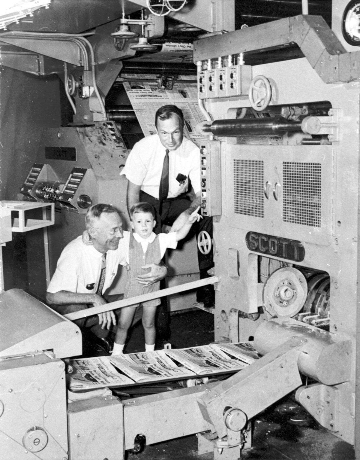 W.E. Page III, W.E. Page (kneeling) with a child in the Bradenton Herald newspaper press room. 1965-66