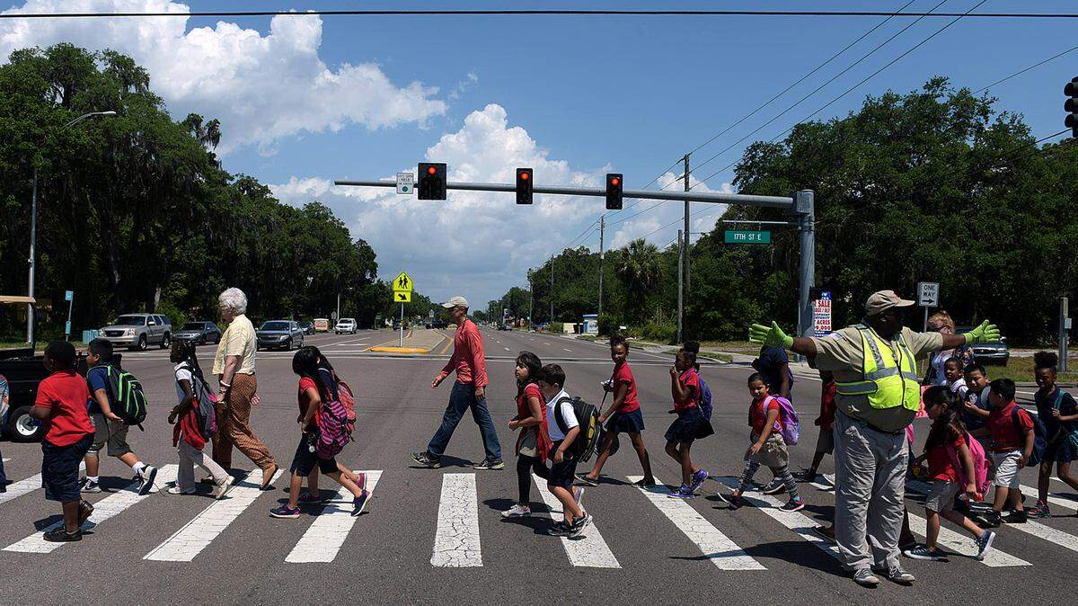 Crossing guard Clyde Poole stops traffic for Manatee Elementary students on SR 64 after school let out for the day last school year. There is no school zone to slow traffic down from the posted 35mph. 
 TIFFANY TOMPKINS/Bradenton Herald