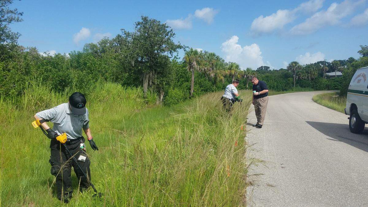 Homicide detective Chuck Butler oversees as crime scene technicians with the Manatee County Sheriff’s Office search the grass where Christopher Alan Boston’s body was found late Wednesday for any possible evidence in the investigation.
