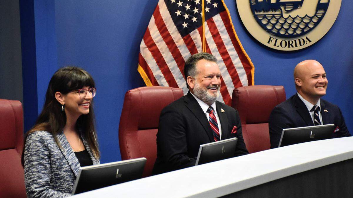 From left: Manatee County Commissioners Amanda Ballard, Mike Rahn and Jason Bearden smile after taking the oath of office and sitting in their seats at the dais for the first time on Nov. 22, 2022.