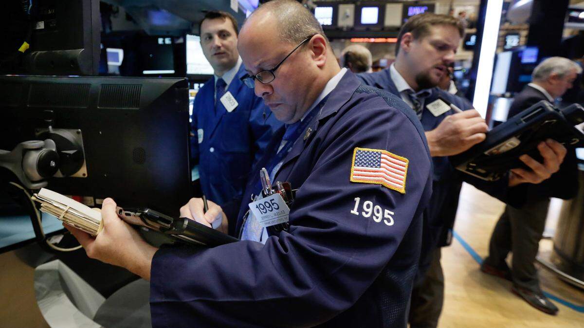 Trader Jeffrey Vazquez, center, works on the floor of the New York Stock Exchange, Monday. Stocks are little changed in early trading as traders look ahead to the start of corporate earnings season. (AP Photo/Richard Drew)