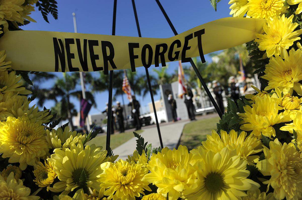 The Manatee County Honor Guard stands in the background seen through a memorial wreath at the Tribute to Heroes Memorial Service at Riverwalk in Bradenton during the 2017 observance.