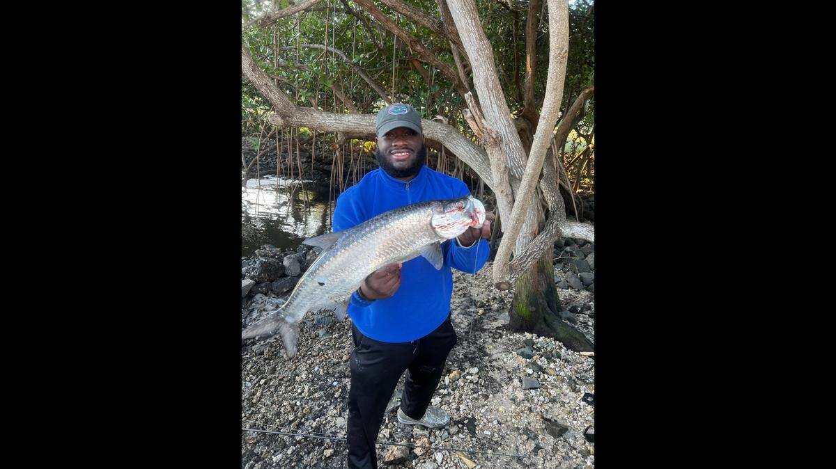 Major Thornton, a social media creator with thousands of followers on Instagram and TikTok, poses with the tarpon he recently caught fishing in a Florida spillway.