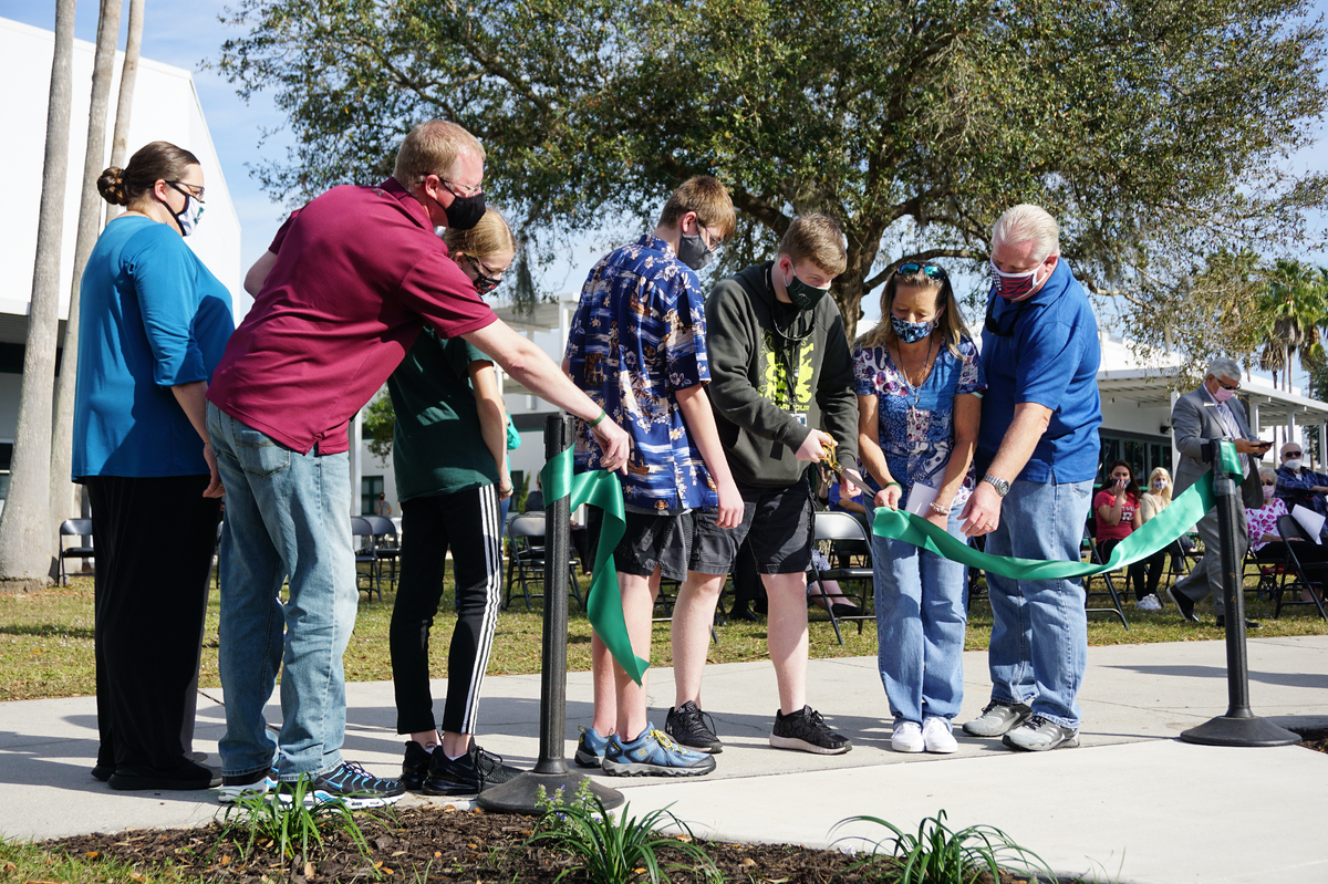 01/27/2021 -- The Coyner and Powers families open the Mustang Memorial Walk at Lakewood Ranch High School, cutting a green ribbon before taking their first steps on the new pathway.